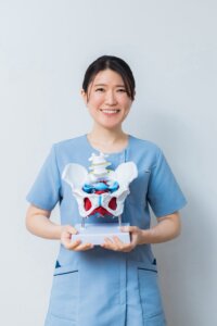 骨盤の模型を持って説明するセラピスト