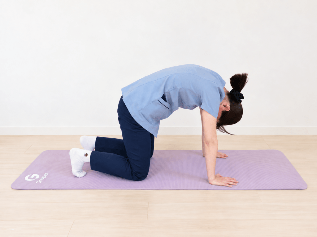 四つばいで息を吐きながら、背中を丸めている様子